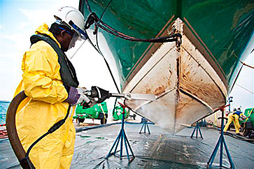 worker cleaning a ship hull by blasting with dry ice