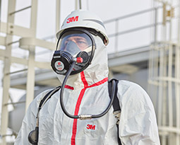 A worker in sealed coveralls uses a 3M Scott facepiece to access supplied air.