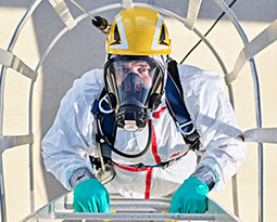 An industrial worker in head-to-toe PPE breathes safely by wearing a 3M Scott full-face air-purifying respirator.