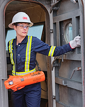 An oil rig employee gets to work carrying an ELSA EEBD emergency breathing air and wears flame retardant clothing from 3M Scott Fire & Safety.