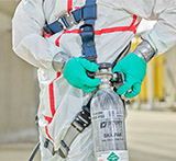 Fully clad in 3M safety apparel, a worker adjusts their supplied air cylinder.