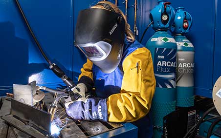 Welder welding with Arcal, SMARTOP Cylinders in the background.