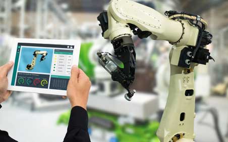 A welder adjusting the setting of a robot.