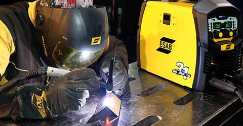 A TIG welder wearing ESAB Personal Protective Equipment (PPE) using an ESAB welding machine