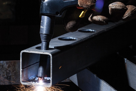 A Powermax user cuts through a box tube by using a handheld torch equipped with HyAccess consumables.