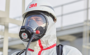 A worker in sealed coveralls uses a 3M Scott facepiece to access supplied air.