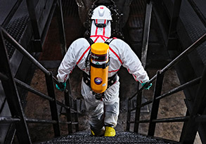 A worker descends into an environment with a hazardous atmosphere, using a 3M Scott SCBA tank to breathe safely.