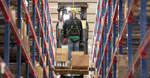 A warehouse worker secured to a personal lift vehicle
