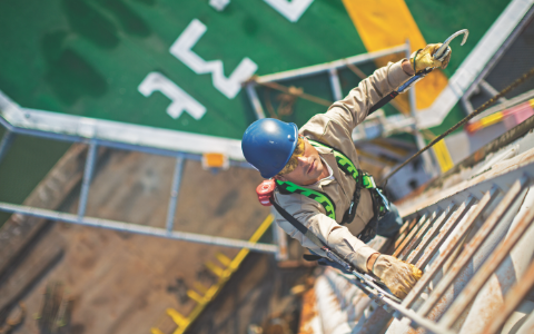 From a top-down view, a worker wearing a Honeywell Miller harness climbs a ladder.