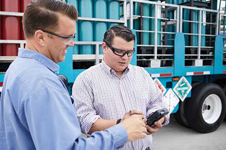 An Airgas driver delivering cylinders to a customer who is signing a digital proof of receipt (POD) on a handheld device.