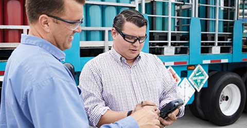 An Airgas driver delivering cylinders to a customer who is signing a digital proof of receipt (POD) on a handheld device.