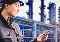 A refinery worker looking at her smartphone.