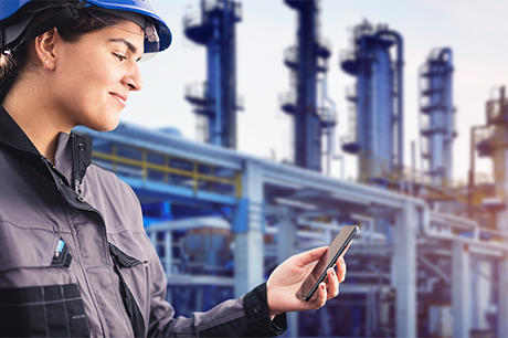 A refinery worker looking at her smartphone.