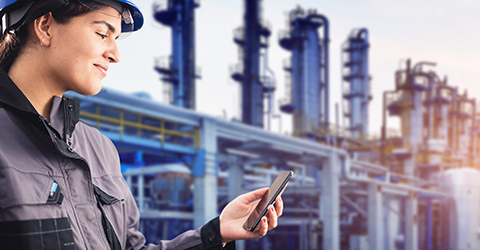 A refinery worker looking at her smartphone.