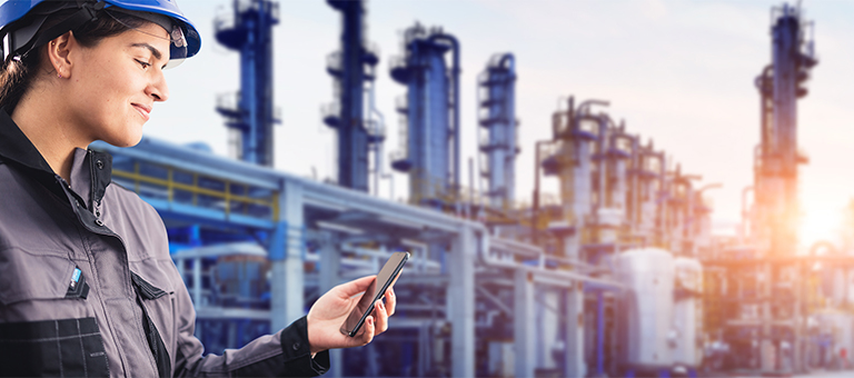 A refinery worker looking at her smartphone.