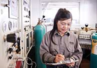 Set in an office, a woman works at a computer and a computer screen showing the Airgas.com homepage can be seen in the background.