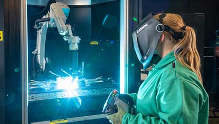 A female welder using a welding robot