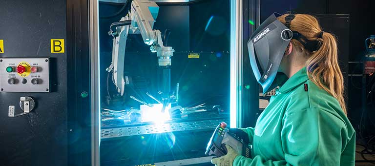 A female welder using a welding robot