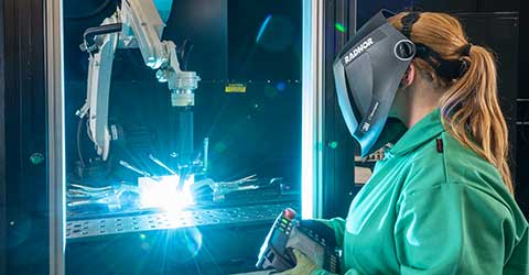 A female welder using a welding robot