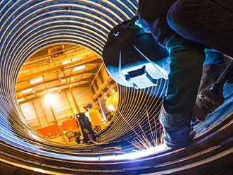 A welder working inside a large pipe