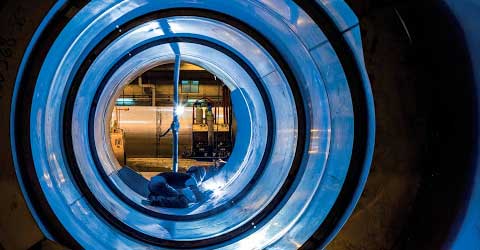 Looking through a large pipe with a welder at the far end