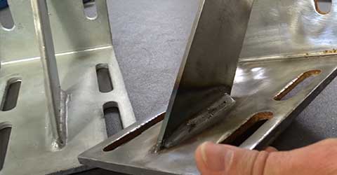 An Advanced Fabrication expert comparing the weld quality on two brackets.