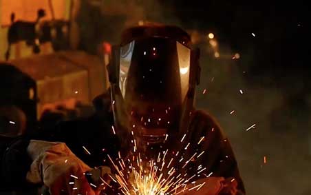 Dramatic image of a welder welding with sparks and smoke
