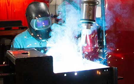A welder overseeing a automated welding process