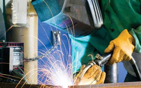 A MIG welder, hunched over a welding project