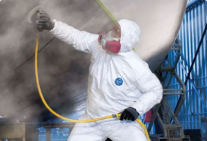 Press to view Worker is protected from hose spray by wearing white DuPont protective gear.