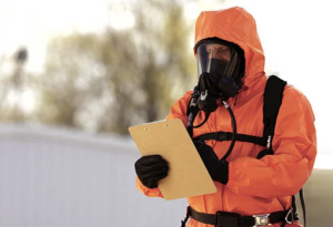 Press to view Worker wearing orange DuPont protective gear is safe from chemicals while looking at clipboard.