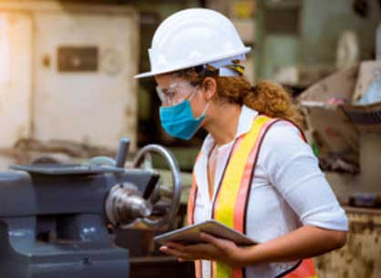 A female industrial plant worker inspecting with a tablet in hand