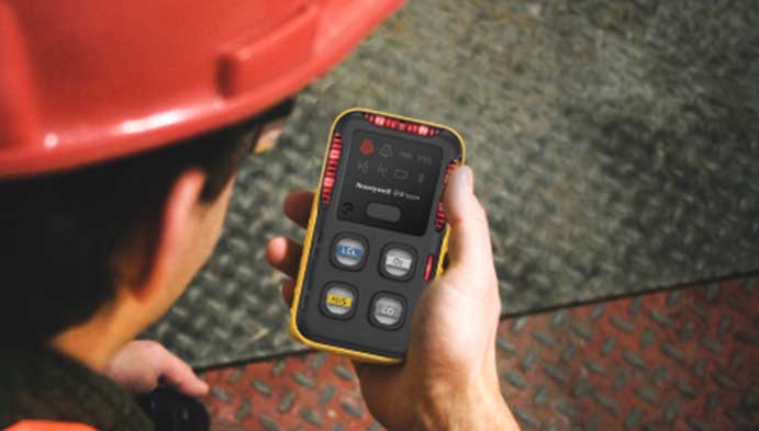 Mid-shot of a Honeywell BW Clip gas detector grasped in a worker’s hand.