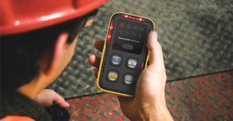 Mid-shot of a Honeywell BW Clip gas detector grasped in a worker’s hand.