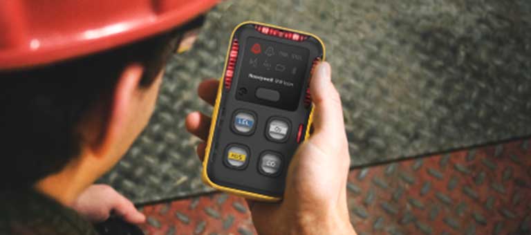 Mid-shot of a Honeywell BW Clip gas detector grasped in a worker’s hand.