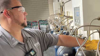 An Airgas Employee filling cylinders in proper PPE.