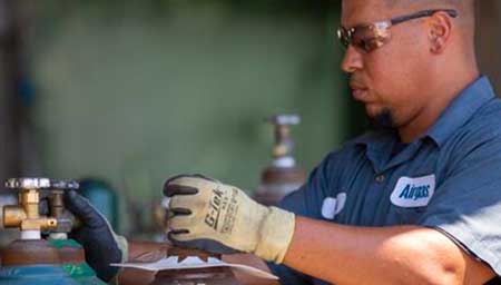 An Airgas technician safely handles a packaged gas cylinder.