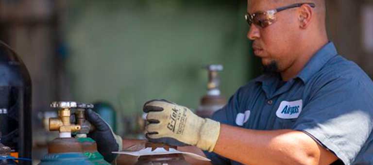 An Airgas technician safely handles a packaged gas cylinder.