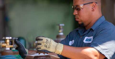 An Airgas technician safely handles a packaged gas cylinder.