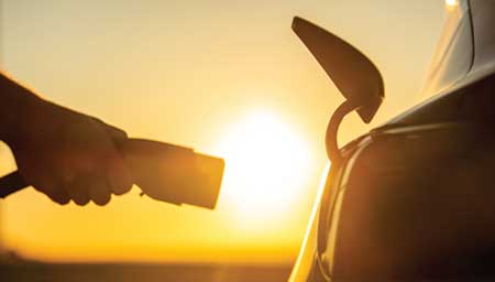 Plugging in an electric vehicle at sunset.