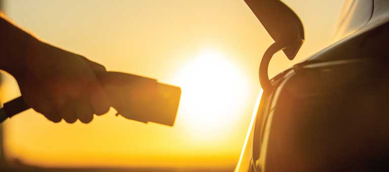Plugging in an electric vehicle at sunset