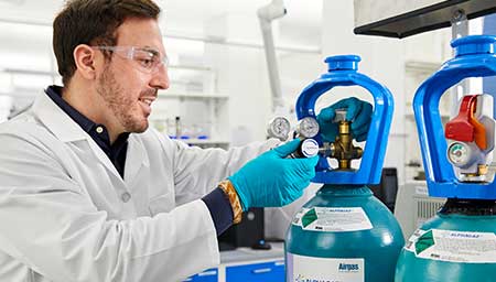 A lab tech attaches a regulator to a SMARTOP cylinder of ALPHAGAZ