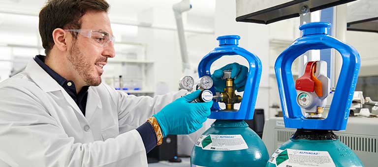 A lab tech attaches a regulator to a SMARTOP cylinder of ALPHAGAZ