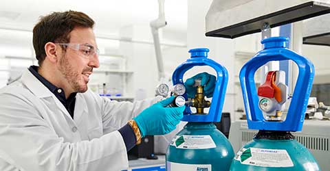 A lab tech attaches a regulator to a SMARTOP cylinder of ALPHAGAZ