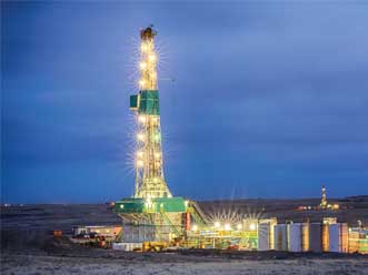 A drilling rig, in the desert, lit up in the evening