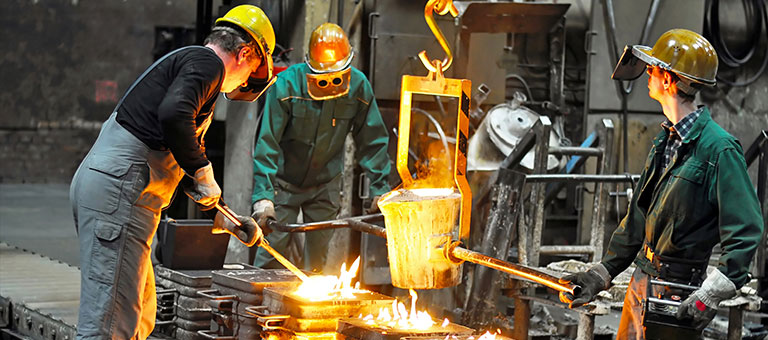 Metal workers pouring molten metal into molds