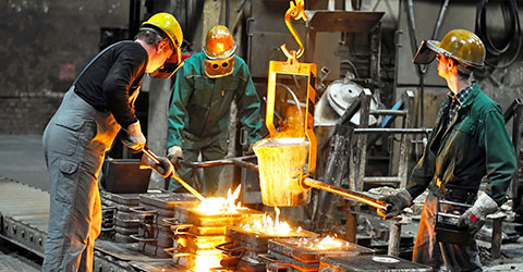 Metal workers pouring molten metal into molds
