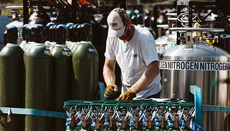 An Airgas fill-plant worker packaging industrial gas cylinders for delivery