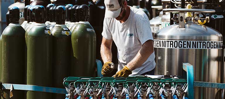 An Airgas fill-plant worker packaging industrial gas cylinders for delivery