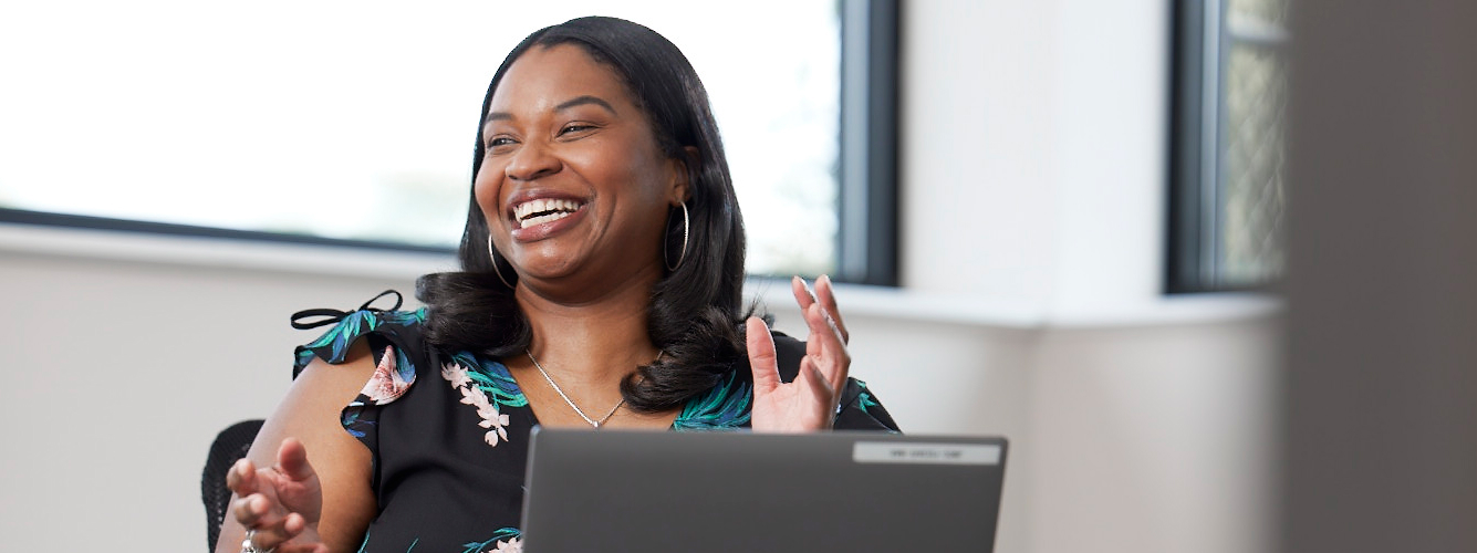 Airgas core business team professional sits at her desk at her laptop smiling. 